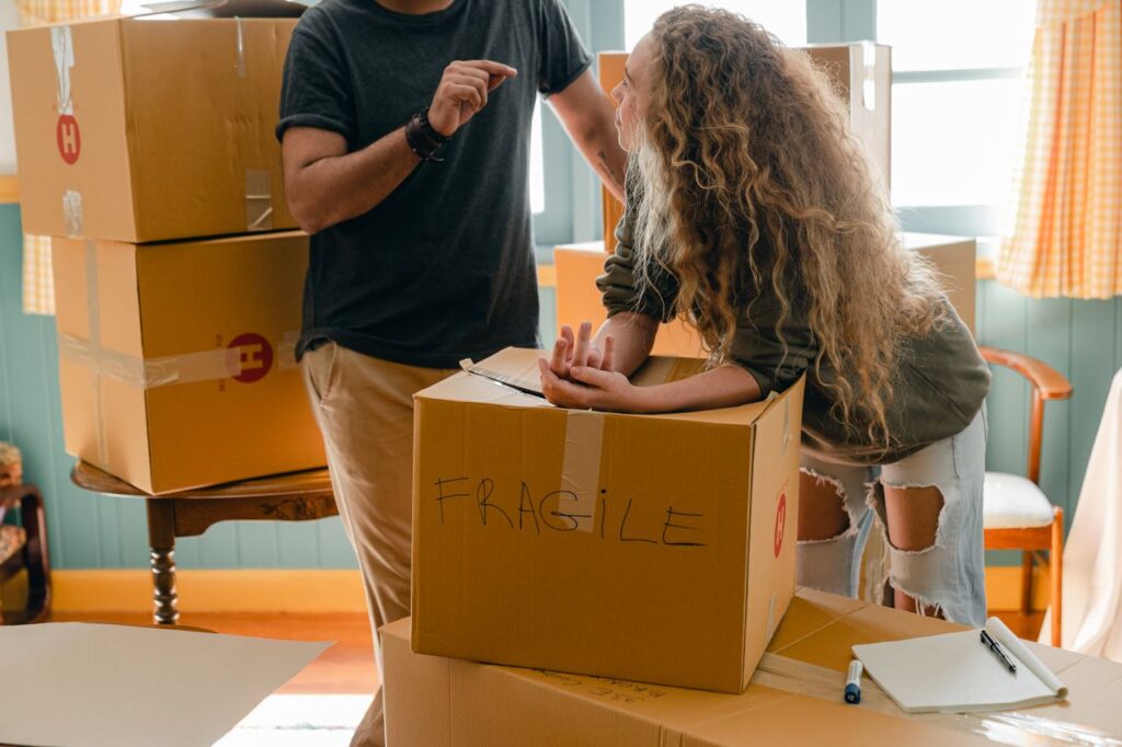 Couple standing near a box marked "FRAGILE" during a residential move