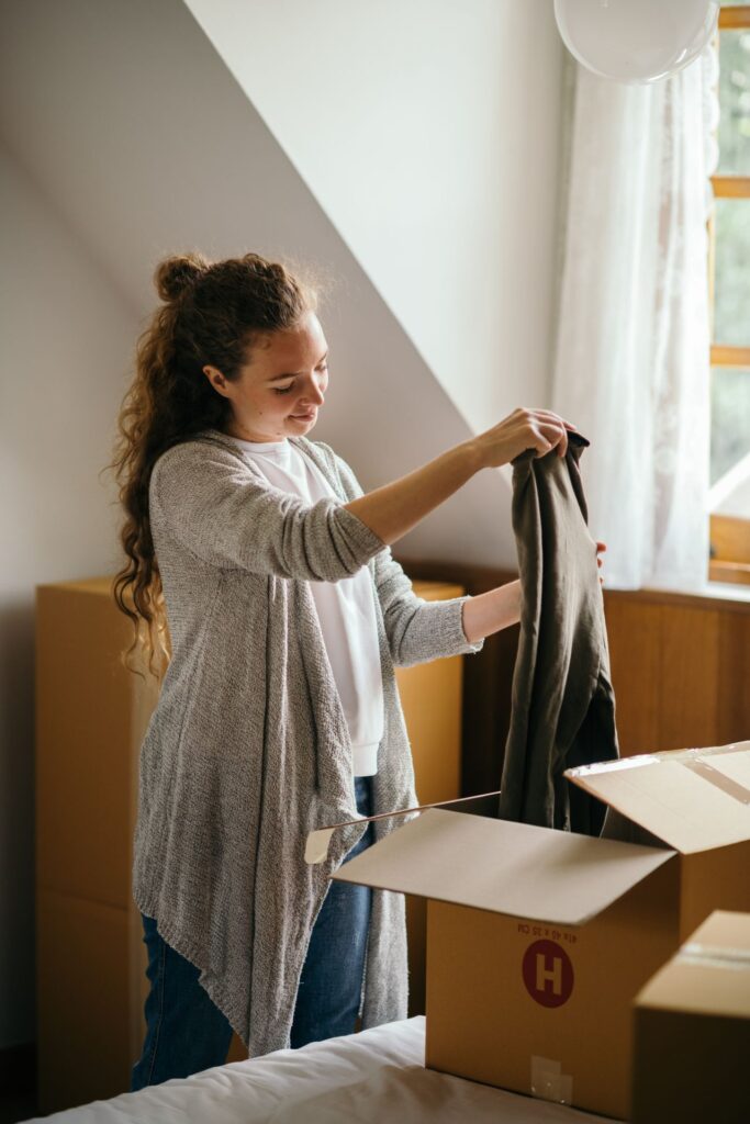Woman packing clothes into a cardboard box before a move