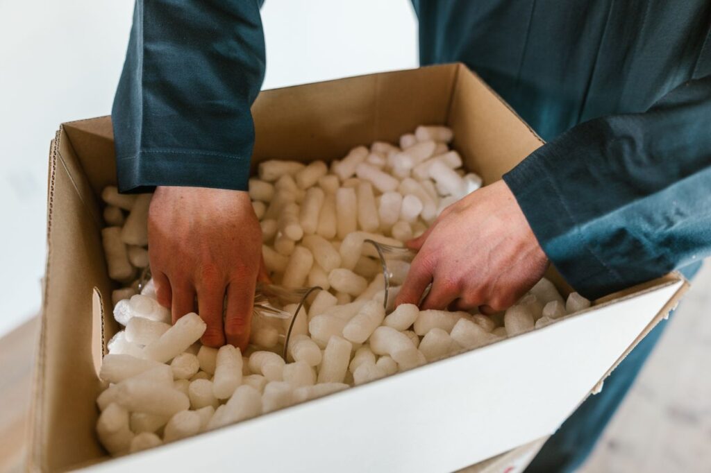 Hands carefully packing glasses into a padded moving box