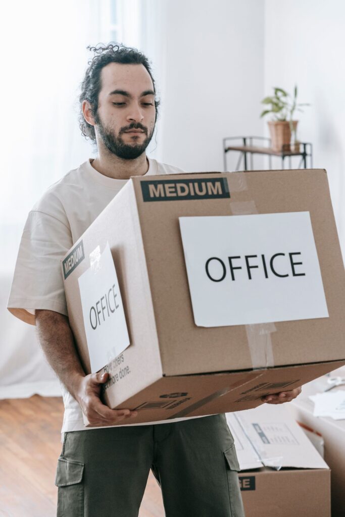 Employee carrying a box labeled "Office" during a tech company relocation