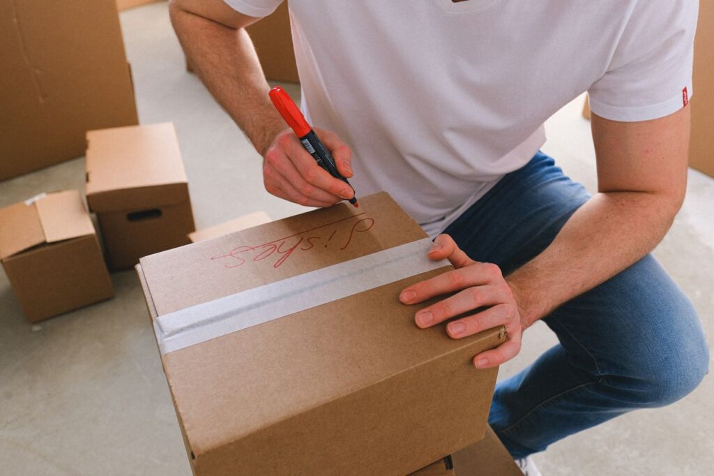 Small business owner labeling moving boxes with a marker