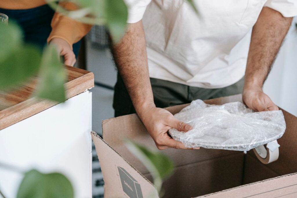 Hands wrapping and packing dishes safely into a moving box