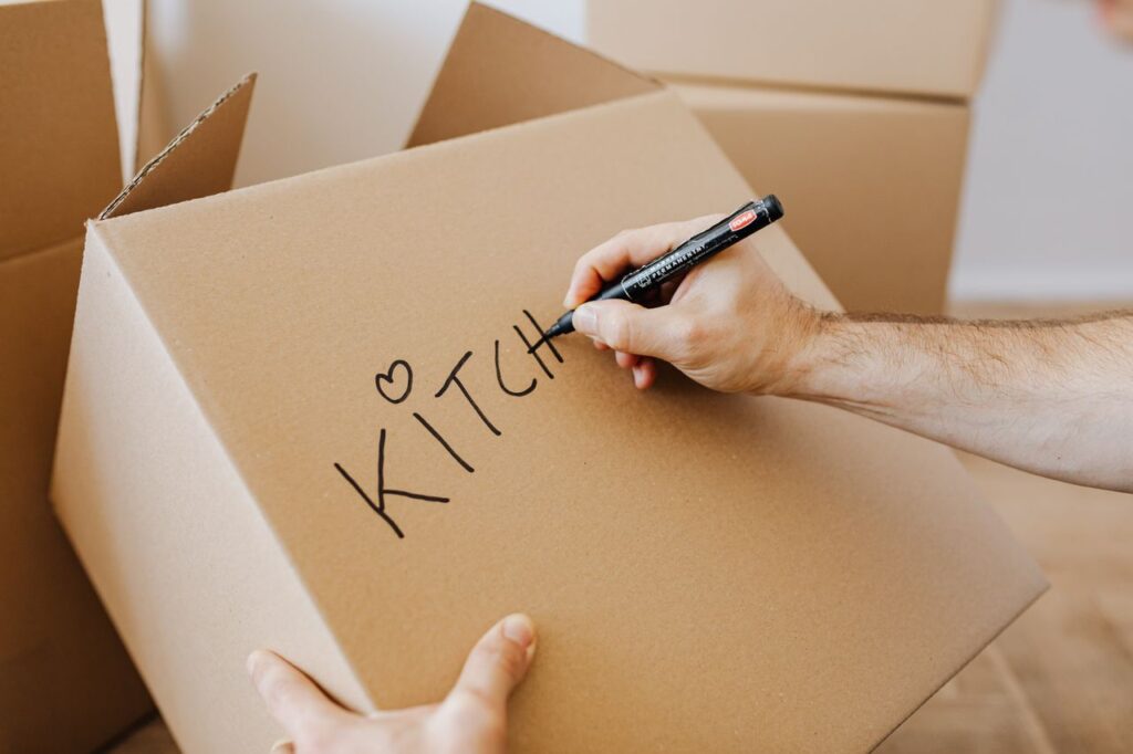 Person writing labels on a moving box with a permanent marker