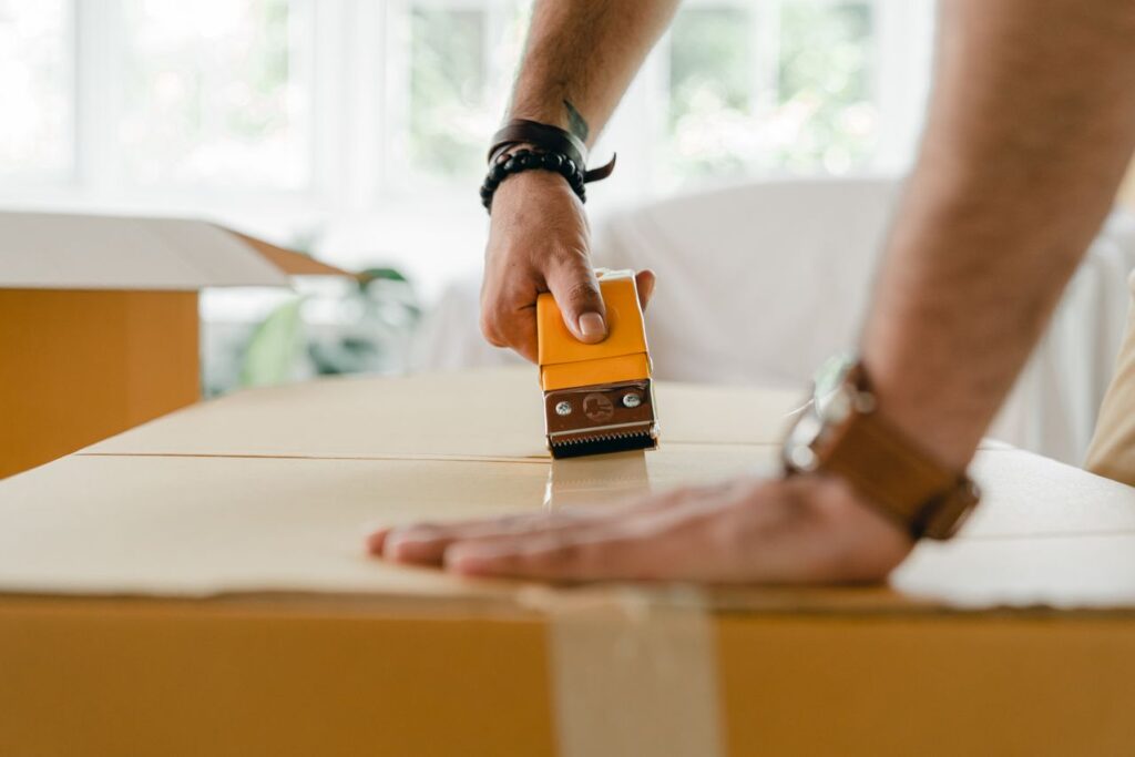 Close-up of a person taping a cardboard moving box shut