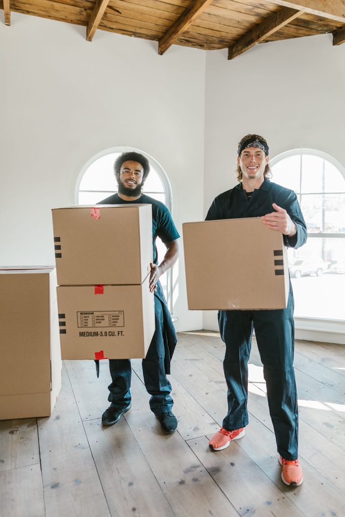 Two professional movers carrying cardboard boxes for a specialty move