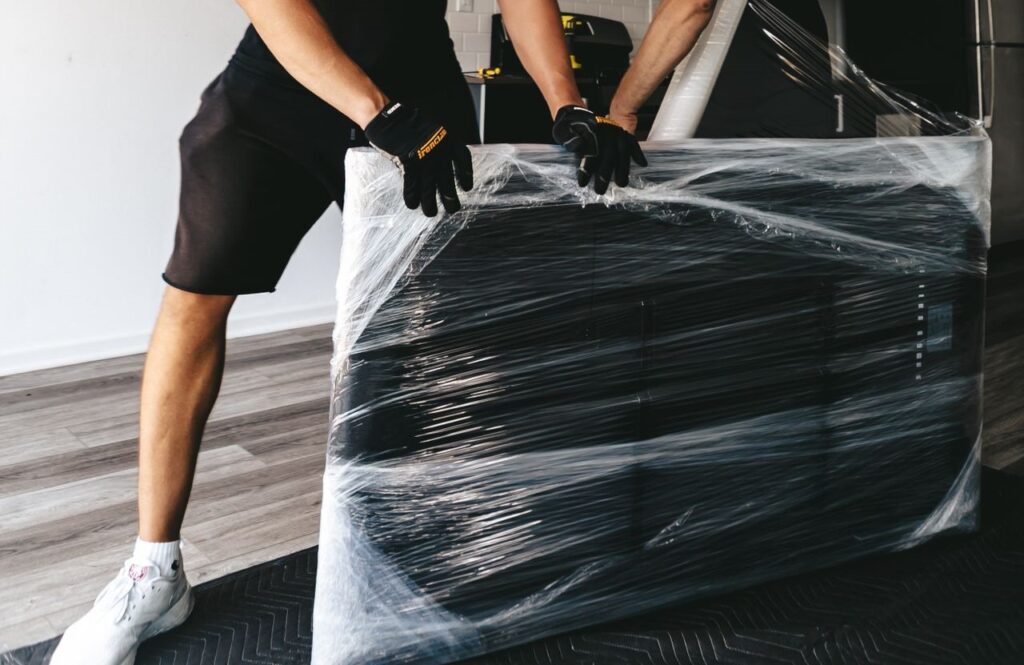 Person carefully packing a flat-screen TV into a protective box for moving